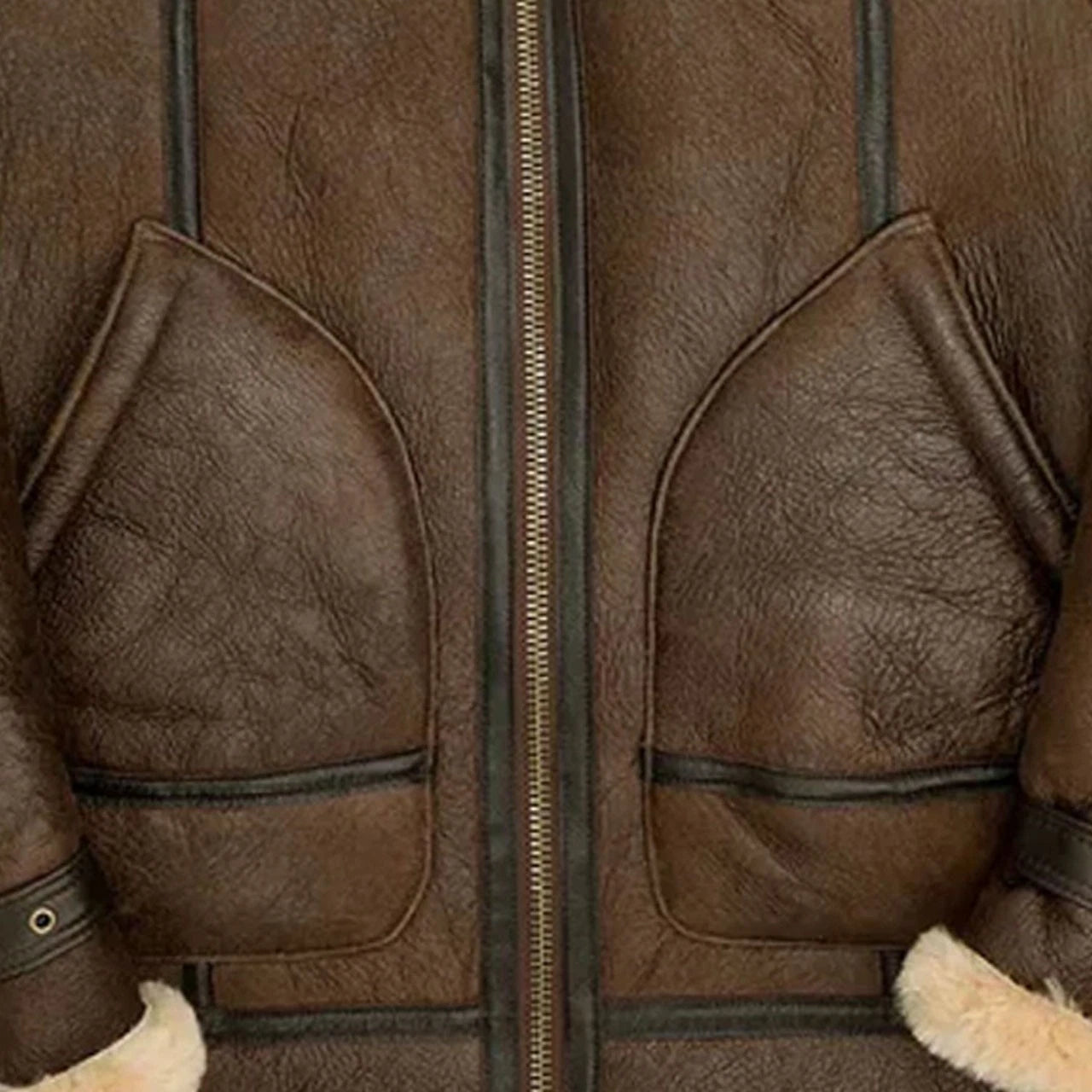 Close-up of a brown leather jacket showing the front zipper, two large flap pockets, and a bit of cream shearling lining at the cuffs.